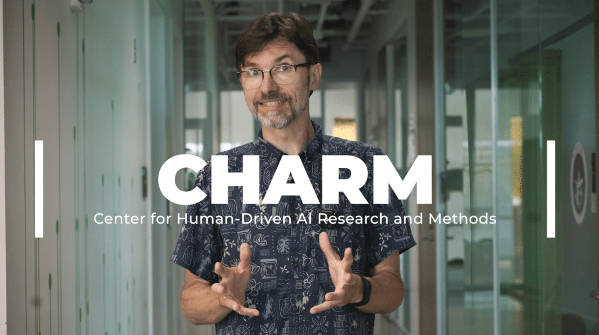 Professor Krzysztof Gajos explaining the CHARM mission while the CHARM logo shows on screen